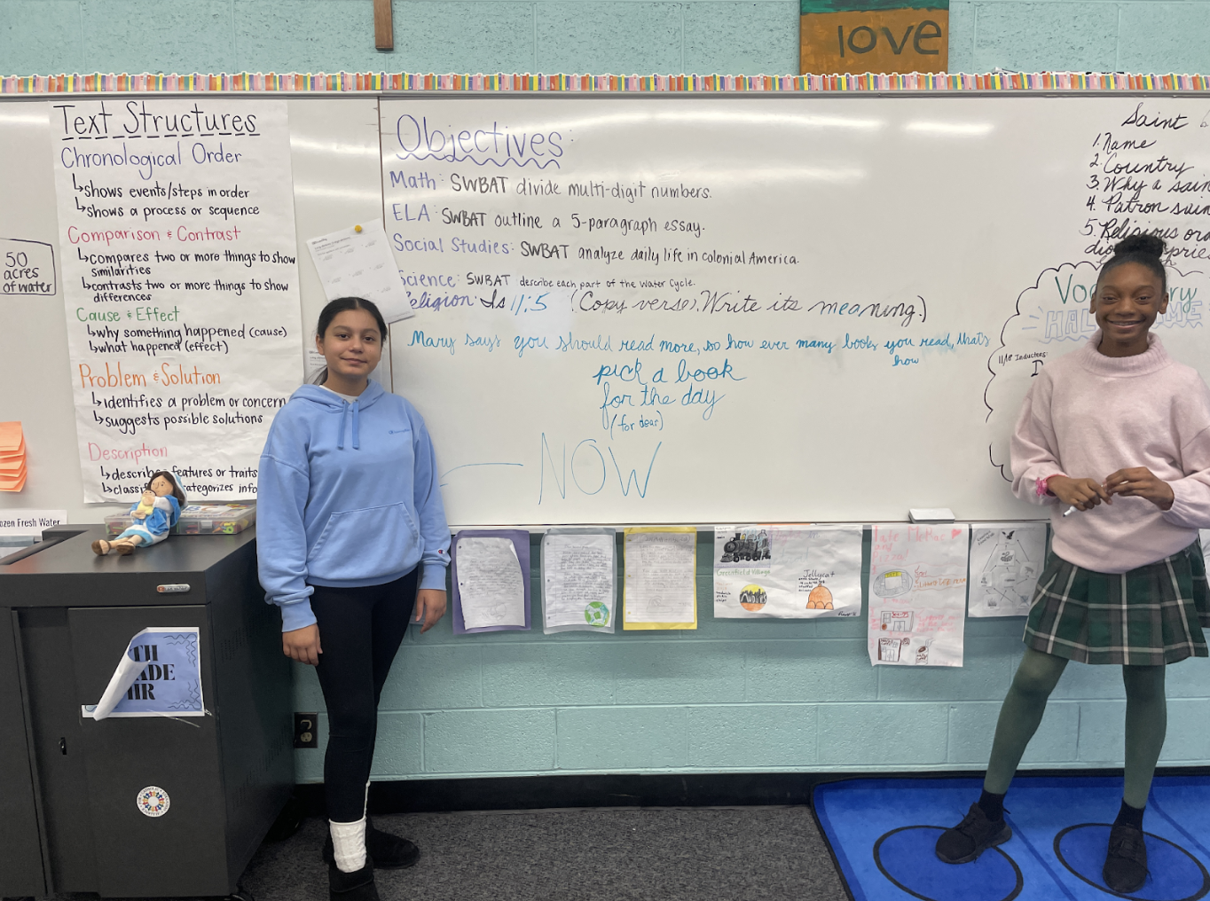 Two students next to white board with note from Mary on the Mantle