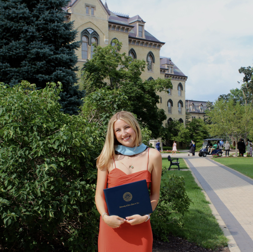 Maddie Schlehuber with her M.Ed. diploma outside the Main Building on graduate day