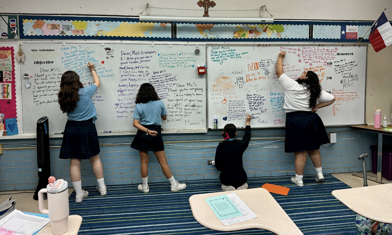 Four students with their backs to the camera writing on a white board